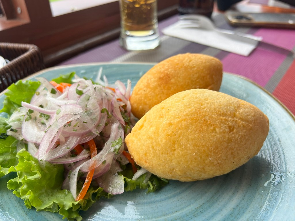 A plate with two golden-compressed balls, likely a type of fried snack, served with a fresh salad of onions and lettuce.